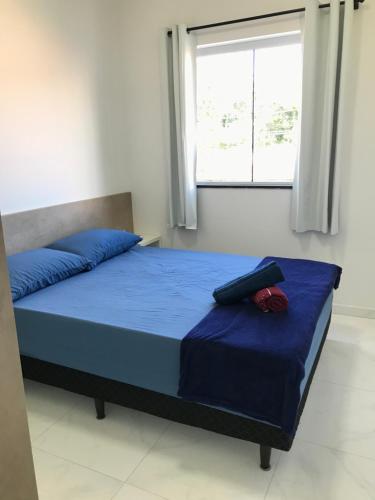 a bedroom with a bed with blue sheets and a window at Apartamento próximo ao Beto Carrero. in Penha