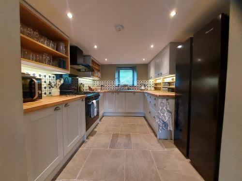 eine große Küche mit weißen Schränken und einem schwarzen Kühlschrank in der Unterkunft Luxurious 4 bedroom Cottage in the Yorkshire Dales in Richmond