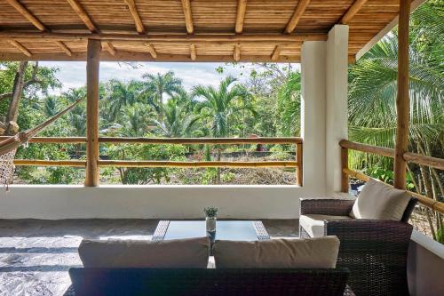 une terrasse avec une table et des chaises et une grande fenêtre dans l'établissement Villa Ananda, à Malpaís
