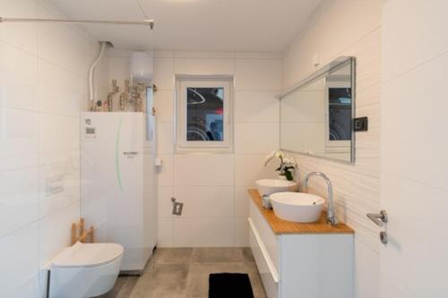 baño blanco con 2 lavabos y nevera en Villa Rosemary Trieste HerMes arT, en Sežana