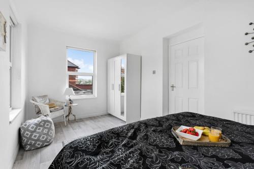 a white bedroom with a tray of fruit on a bed at Little Place in Torquay