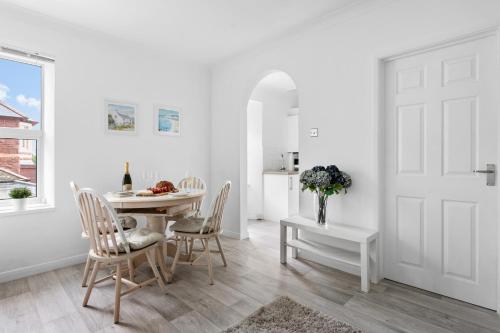 a white dining room with a table and chairs at Little Place in Torquay