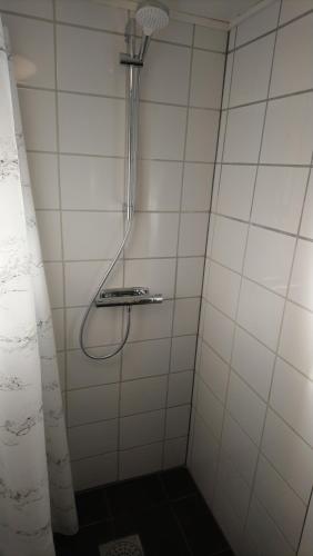 a shower in a white tiled bathroom at Gäststuga i centrala Ystad in Ystad