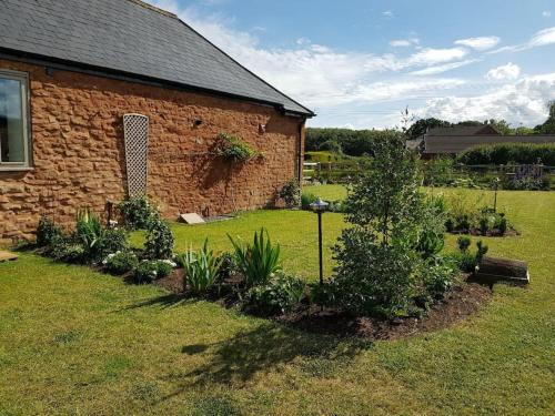 a brick building with plants in front of a yard at Sweet Meadow Lodge in Exeter