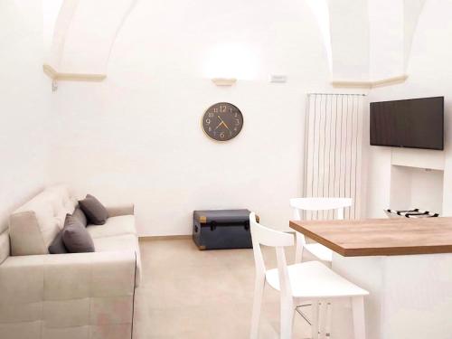 a living room with a couch and a clock on the wall at Teorema Suites in Nardò