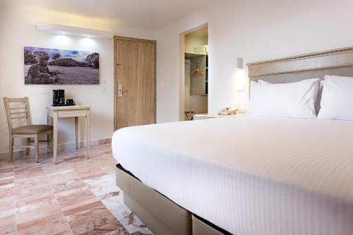a bedroom with a large white bed and a desk at Gamma Villahermosa Centro in Villahermosa