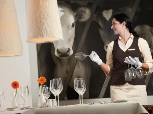 a woman is pouring wine into a wine glass at aja Fürstenhaus am Achensee in Pertisau