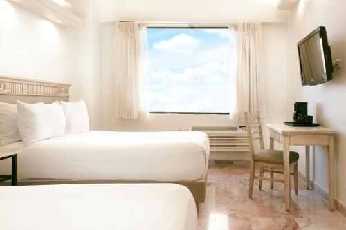 a hotel room with two beds and a desk and a window at Gamma Villahermosa Centro in Villahermosa