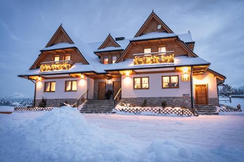 波羅寧的住宿－Apartamenty ROZETA Poronin，雪覆盖的房屋,晚上有灯