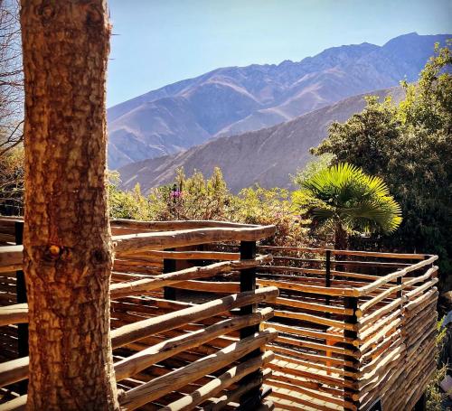 a wooden fence with a tree and mountains in the background at Hotel El Milagro in Pisco Elqui