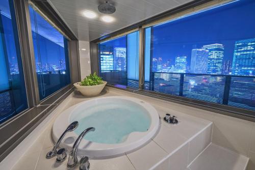 La salle de bains est pourvue d'une baignoire et offre une vue sur la ville. dans l'établissement Harmonie Embrassee, à Osaka