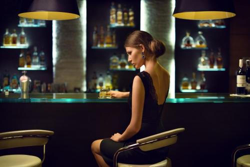 a woman sitting in a chair at a bar at Odyssey ClubHotel Wellness & SPA Adults Only in Kielce