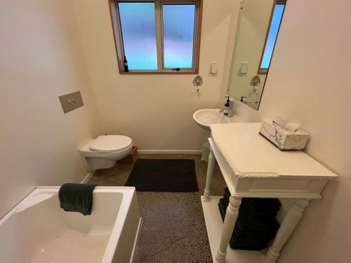 a bathroom with a tub and a sink and a toilet at Beech Hill - Pet Friendly Holiday Home in Tasman