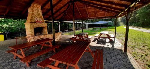 a pavilion with picnic tables and a brick oven at Dom nad rzeką Legą in Sypitki