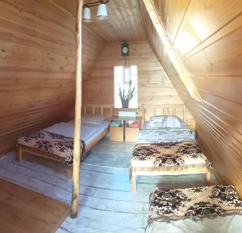 a bedroom with two beds in a wooden cabin at Casa Miliza - Agropensiunea şi Punctul Gastronomic Local, în vecinătatea castelului Salbek in Petriş