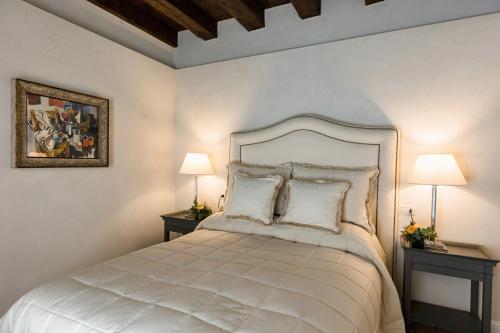 a bedroom with a white bed with two lamps at CORTE SAGGIN Charme Relais in San Pietro in Cariano
