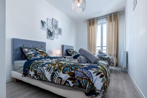 um quarto com uma cama com um edredão azul e branco em Appartement lumineux de standing em Drancy