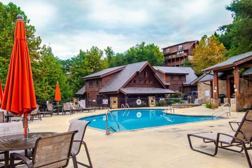 a pool with chairs and a table with an umbrella at Higher Ground Condo with Mountain and Golf View in Pigeon Forge