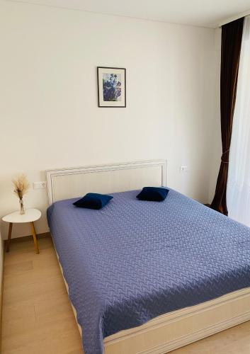 a bedroom with a bed with a blue comforter at Apartamentai “Viola” Juodkranteje in Juodkrantė