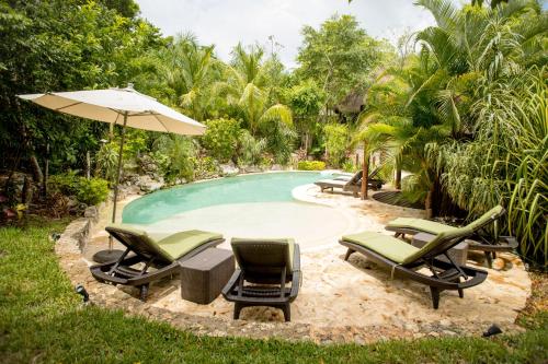a pool with lounge chairs and an umbrella at ALDEA JO-YAH in Tulum
