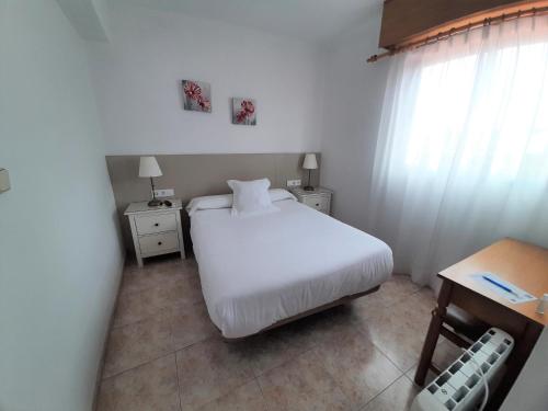 a small bedroom with a white bed and a table at Hotel La Terraza in Miño