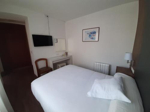a bedroom with a white bed and a television at Hotel La Terraza in Miño