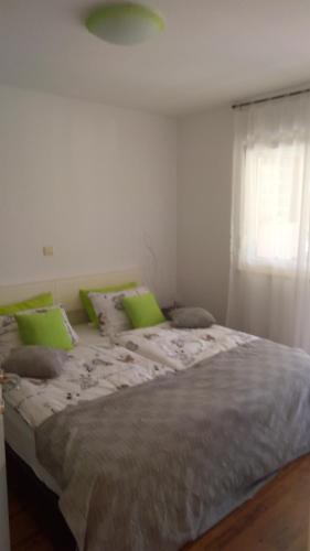 a large bed with green pillows and a window at Apartma Andrea in Medulin
