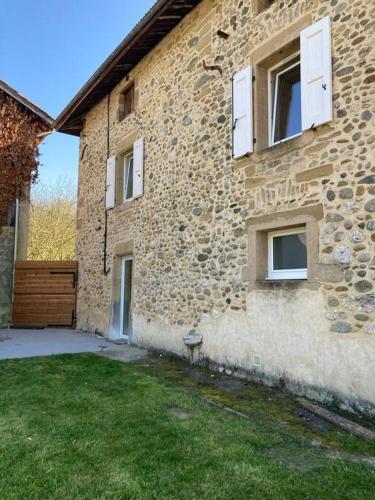 - un bâtiment en pierre avec des fenêtres et une pelouse dans l'établissement Les Séchoirs piscine et spa privatifs, à Saint-Romans