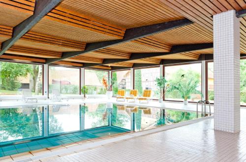 a swimming pool in a house with glass windows at Hotel Hof Sudermühlen in Egestorf