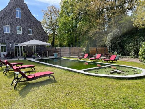 a swimming pool with red chairs and a building at dS Hotel Gronau in Gronau