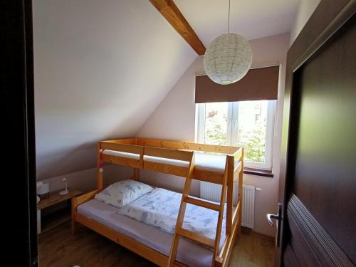a bunk bed in a room with a ladder and a window at Słoneczne Wzgórze in Jeżów Sudecki