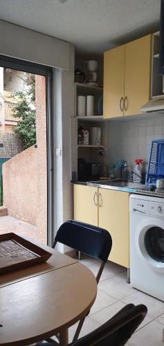 une cuisine avec une table et une machine à laver dans l'établissement LA VAGUE BLEUE, à Porticcio