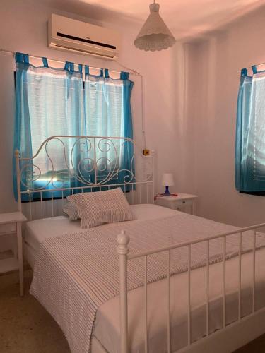 a bedroom with a white bed with blue curtains at Kissonerga beach apartment in Paphos