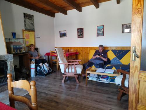 un hombre sentado en un sofá en una sala de estar en Albergue La Senda, en Rabanal del Camino