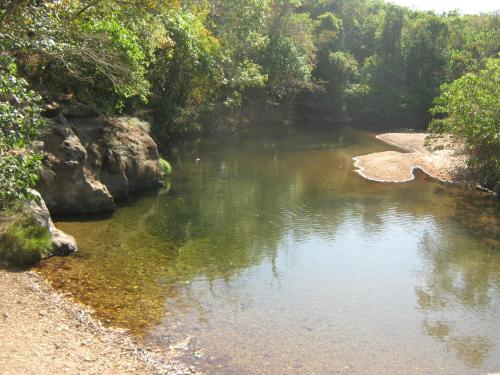 einen Fluss mit Felsen und Bäumen im Hintergrund in der Unterkunft Sítio Aroeira Chalés in Sao Jorge