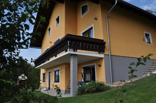a yellow building with a balcony on the side of it at Ferienwohnung Höbart in Dorfstetten