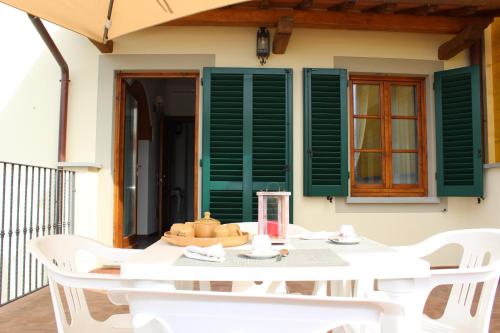 a white table with white chairs and green shutters at Art Apartment Chianti Family in Lappeggi