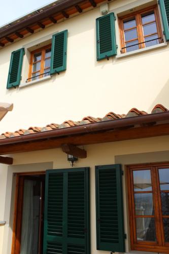 a white house with green shutters and windows at Art Apartment Chianti Family in Lappeggi