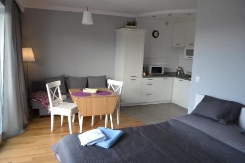 a living room with a table and a kitchen at Darłówko Apartament Morski VI in Darłówko