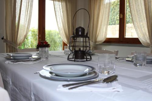 a table with a white table cloth with plates and a lamp at Art Apartment Chianti Family in Lappeggi