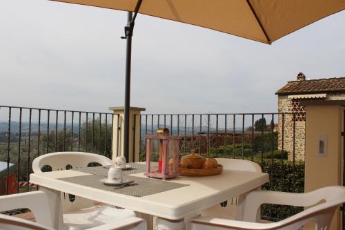 a white table and chairs with an umbrella on a balcony at Art Apartment Chianti Family in Lappeggi