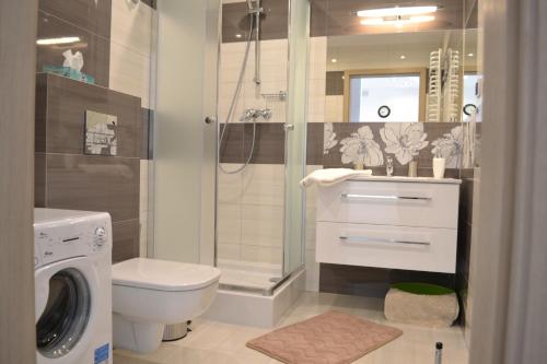 a bathroom with a shower and a toilet and a washing machine at Darłówko Apartament Morski VI in Darłówko