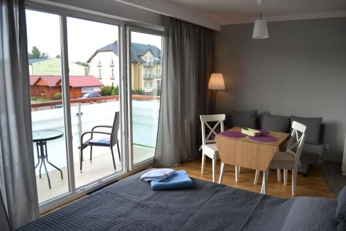 a bedroom with a bed and a table and a balcony at Darłówko Apartament Morski VI in Darłówko