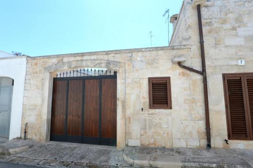 - un bâtiment en pierre avec une porte en bois et 2 fenêtres dans l'établissement Dimora Monte Grappa, à Alberobello