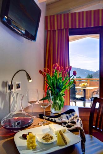 a table with a plate of food and a vase of flowers at Hotel Sassella in Grosio
