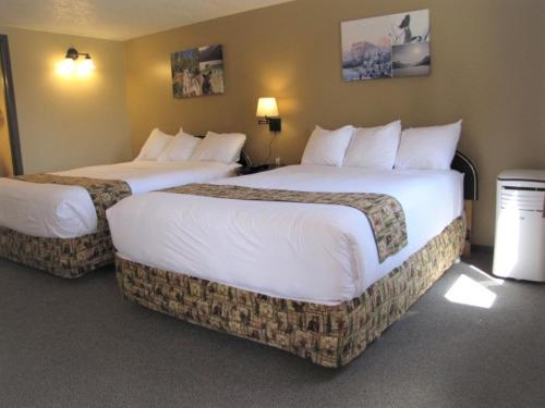 two beds in a hotel room with white sheets at Bear Country Inn and Suites in Mountain View