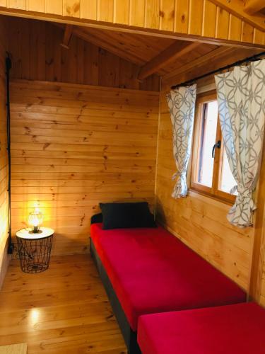 a room with a red bed in a wooden room at Domki letniskowe przy lesie - "U Łastka" in Bartołty Wielkie