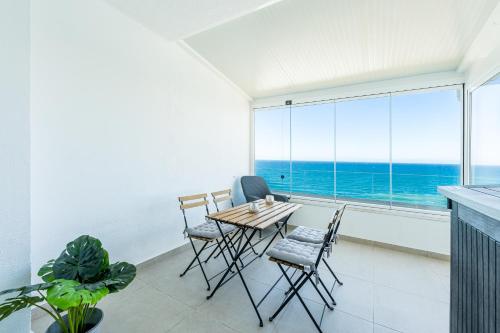 a dining room with a table and chairs and a large window at KEYWISE Beachhouse OceanBlue in Benalmádena