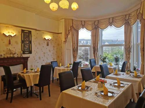 un restaurante con mesas, sillas y ventanas en Athol Park Guest House, en Port Erin
