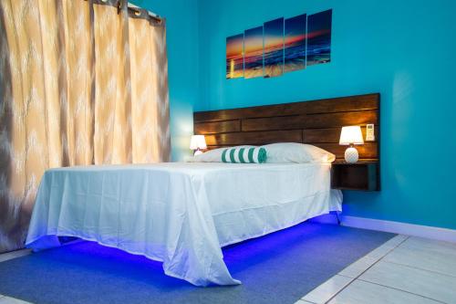 1 dormitorio con 1 cama blanca y paredes azules en Bliss on the Bay family en West End